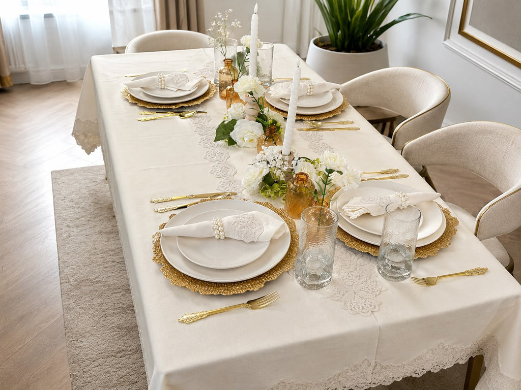 Empire Lumina 26-piece off-white 100% Turkish linen dining table set featuring an embroidered tablecloth, matching table runner, 12 embroidered napkins with 12 pearl napkin rings, elegant white dinnerware, and gold flatware.