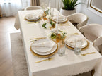 Empire Lumina 26-piece off-white 100% Turkish linen dining table set featuring an embroidered tablecloth, matching table runner, 12 embroidered napkins with 12 pearl napkin rings, elegant white dinnerware, and gold flatware.