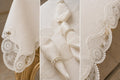 Luxury off-white stain-resistant Turkish linen tablecloth close-up showing embroidered lace border, matching embroidered napkins, pearl napkin rings, and premium craftsmanship details.