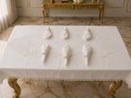 Luxury off-white stain-resistant Turkish linen 26-piece dining set with tablecloth, matching runner, 12 embroidered napkins, and 12 pearl napkin rings, styled on a gold dining table in a luxury marble interior.