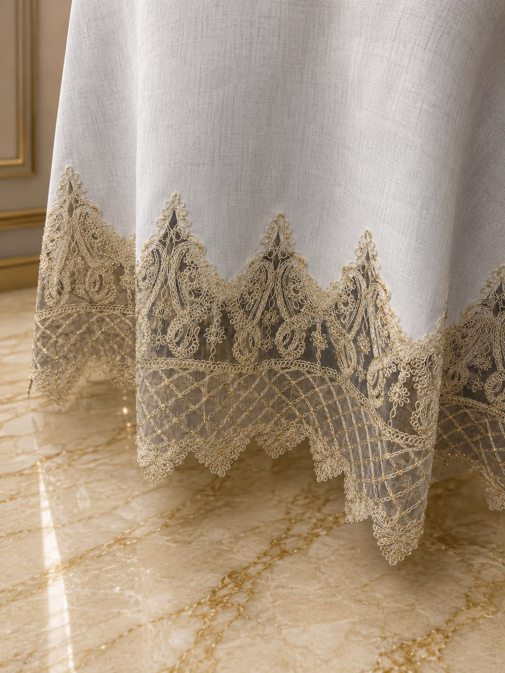 Close-up of Empire Lumina round tablecloth featuring intricate gold lace embroidery and elegant scalloped detailing.
