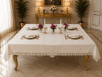 Luxury off-white stain-resistant Turkish linen tablecloth set styled on a gold dining table with marble flooring, white dinnerware, floral centerpieces, and elegant place settings.